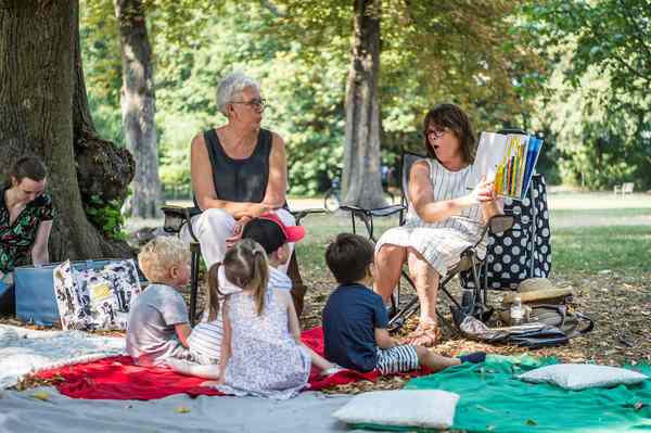 Voorlezers van leeslekker lezen voor aan kinderen in het park.